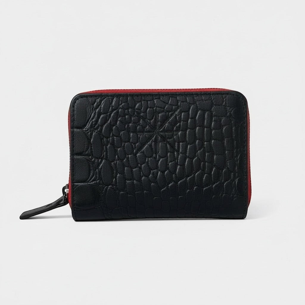 Portefeuille zippé noir La Stella en cuir embossé croco avec doublure rouge. Compact et fonctionnel, idéal pour cartes et billets.