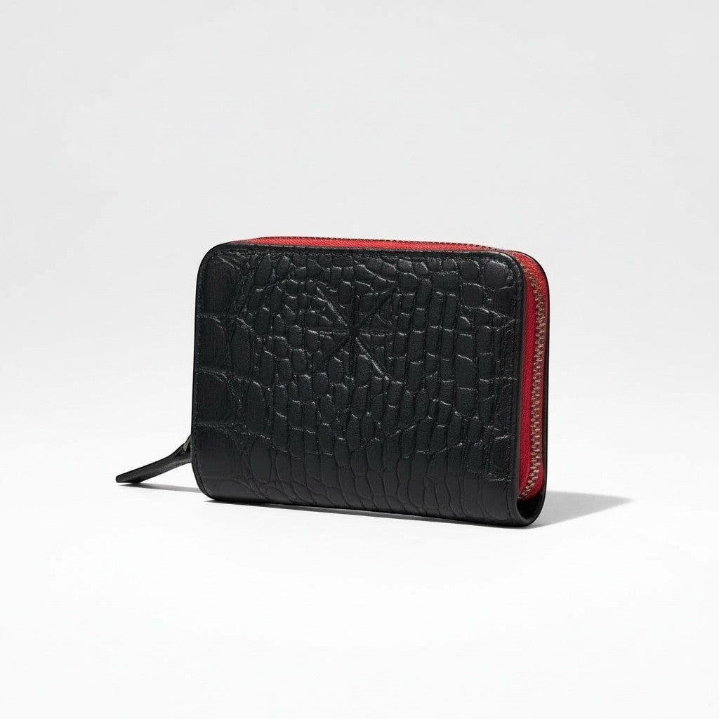 Portefeuille zippé La Stella en cuir noir texturé croco avec doublure rouge contrastante. Fermeture éclair intégrale et logo discret.